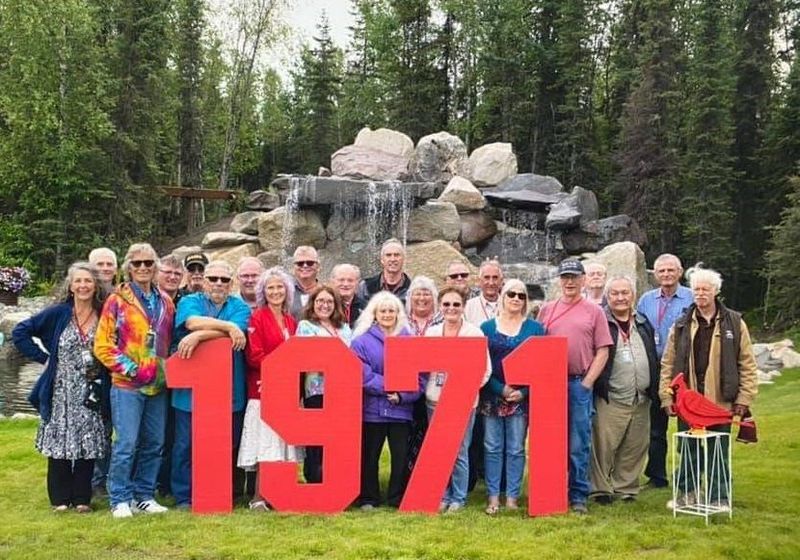 Class of 1971 reunion posing behind red 1971 letters at the waterfall