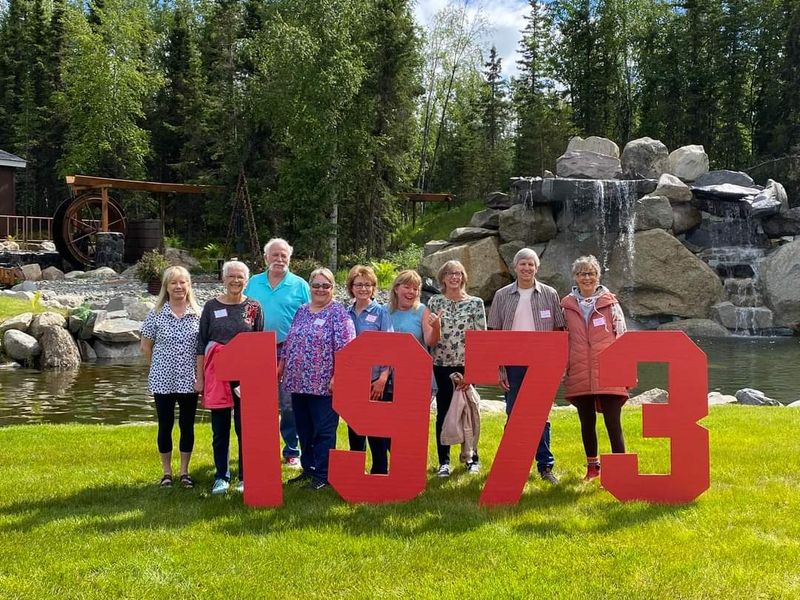 Class of 1973 reunion behind red 1973 letters by the waterfall