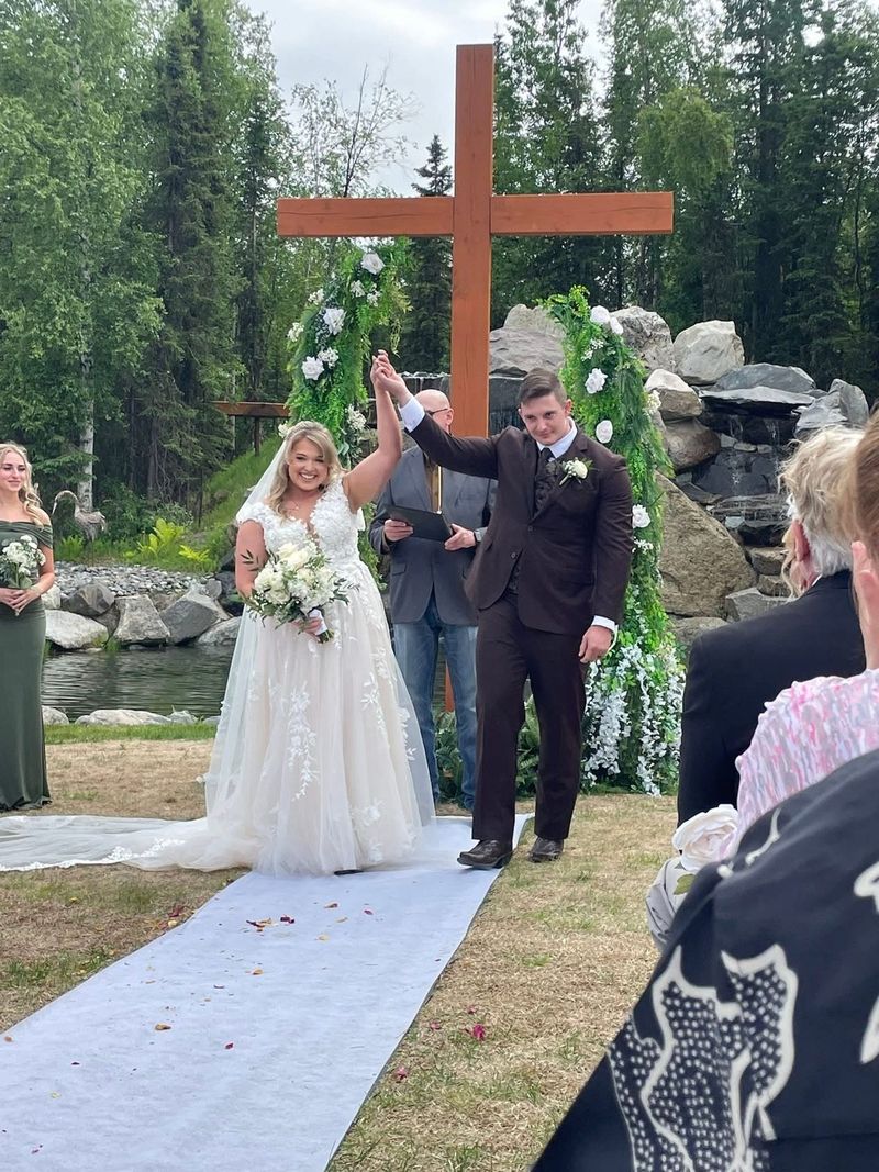 A newly married couple celebrating at the cross arch after their ceremony