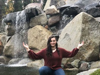 A woman with arms outstretched in front of the waterfall