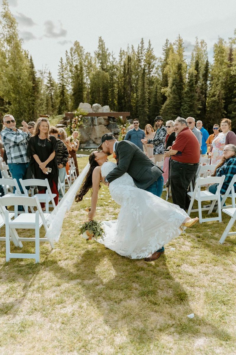 A groom dipping his bride for a kiss in the aisle