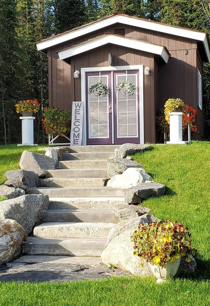 The she-shed with welcome sign, stone steps and flower pots