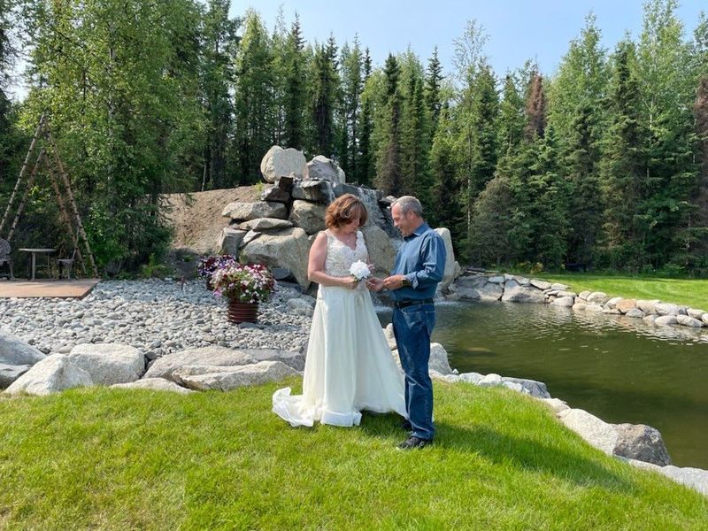 A couple exchanging vows on the grass beside the pond