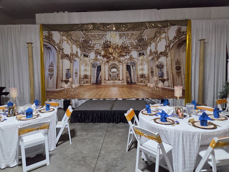 An indoor reception with a ballroom backdrop and blue napkins