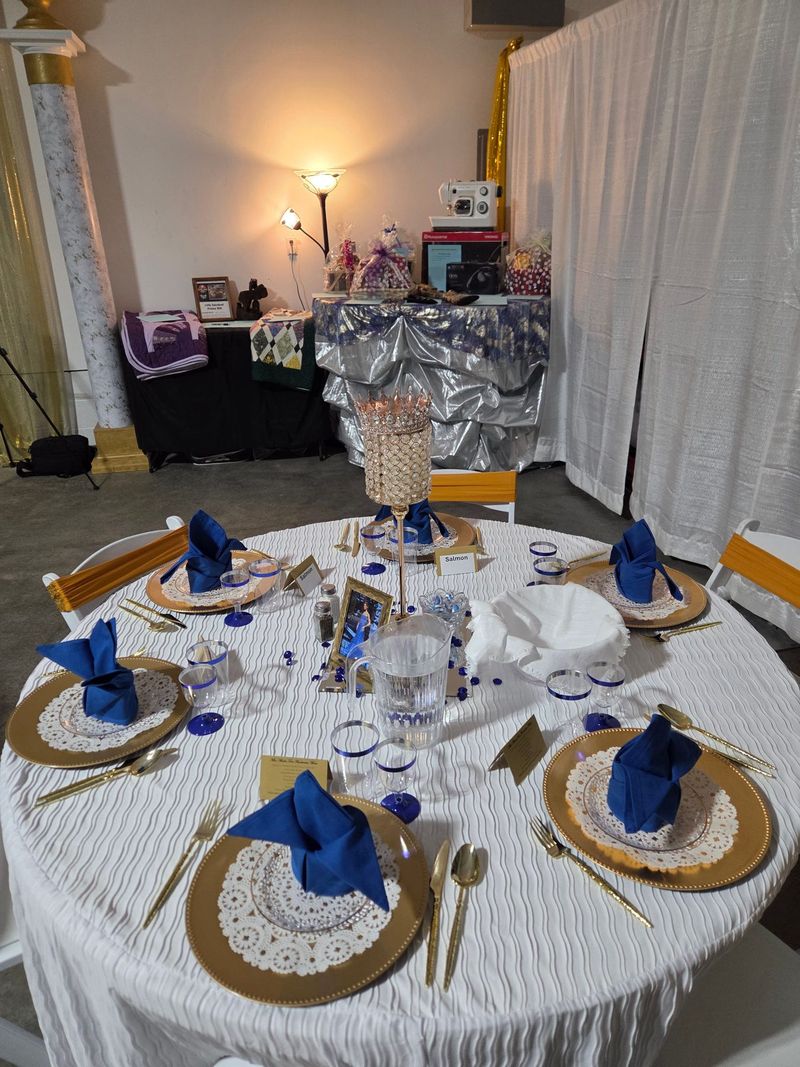 A round table set with gold chargers and blue napkins