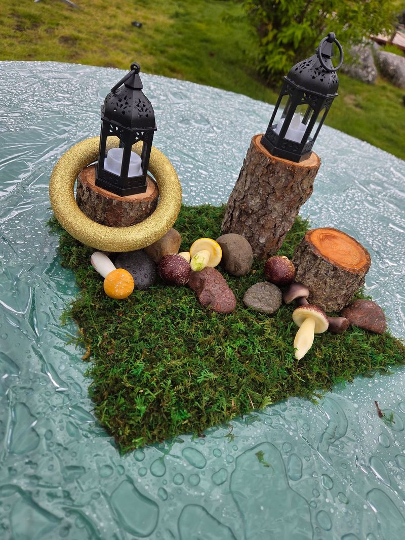 A centerpiece of moss, mushrooms and lanterns