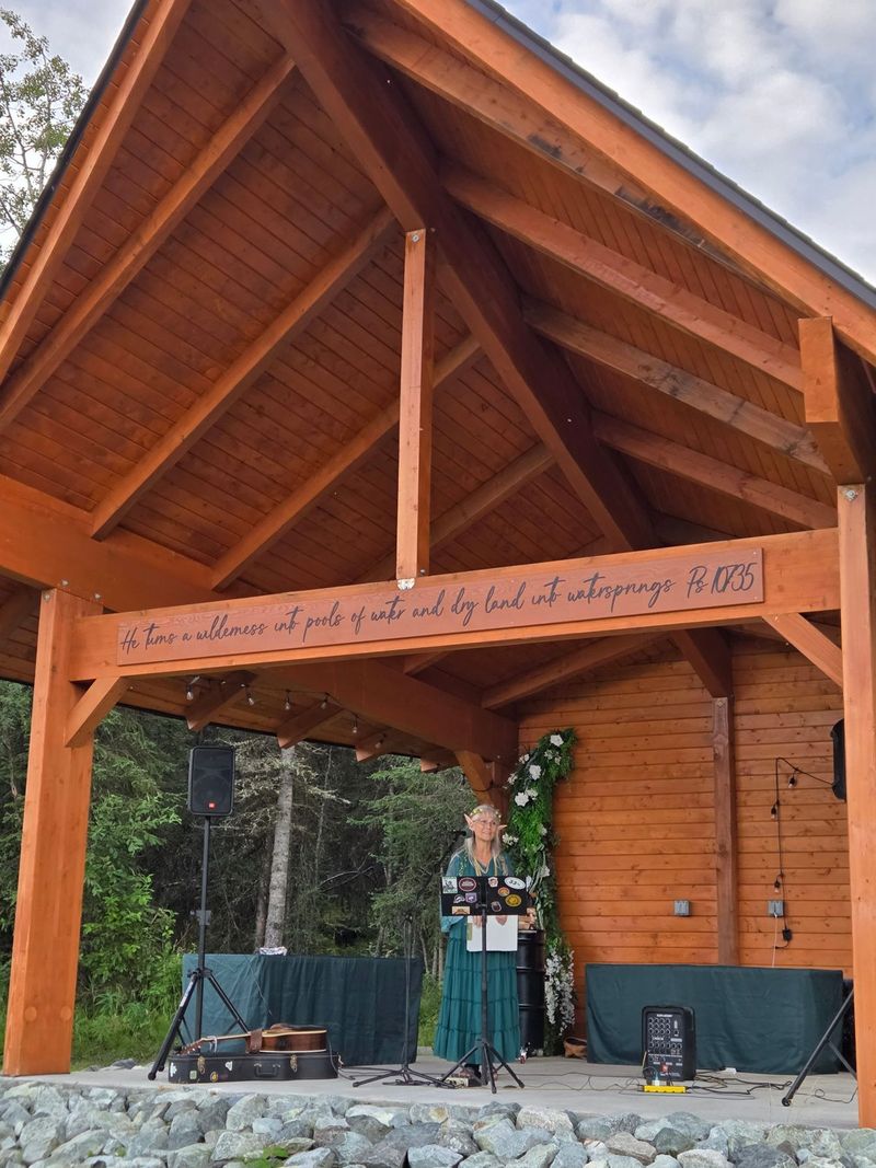 A speaker on the covered stage with its carved verse beam